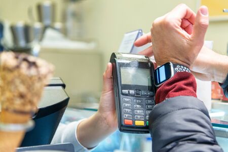 A man hand holding and using of smart watch paying for ice cream to a cashier. Shopping concept.