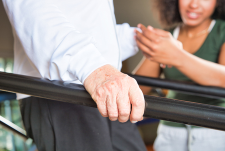 Elderly woman making rehab at bars, assisted by nurse. Detail on hands.の写真素材