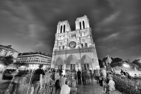 PARIS - JUNE 2014: Notre Dame Cathedral at night with tourists. Notre Dame is visited by 12 million people every year.のeditorial素材