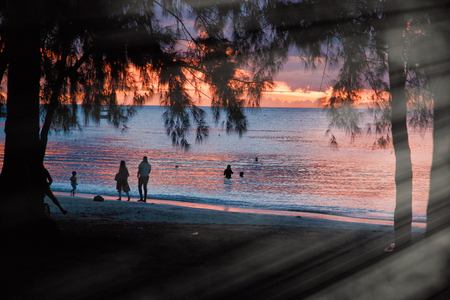 Silhouettes of people walking on the beach at dusk.の写真素材