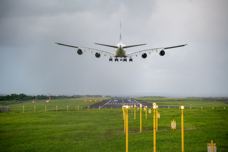 Giant aircraft landing at the airport with runway in the background. Back view.