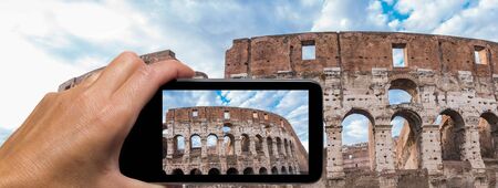 Woman hand with smartphone taking a picture of Colosseum in Rome.の写真素材