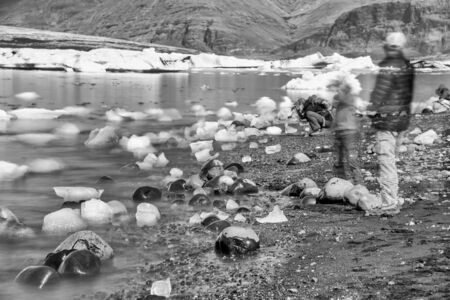 Jokulsarlon lake with icebergs on a sunny day, Iceland. Long exposure view with moving people and blocks of ice.の写真素材