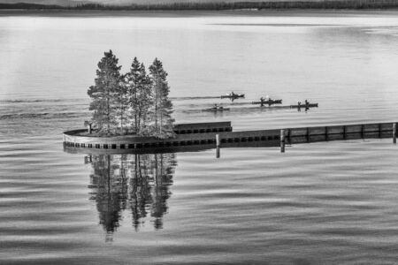 Canoes at sunset along Yellowstone Lake with trees water reflections.の写真素材
