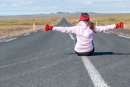 Traveller woman sitting on the road. Strength and independence. Woman day. Tourism, freedom and holiday concept.の写真素材