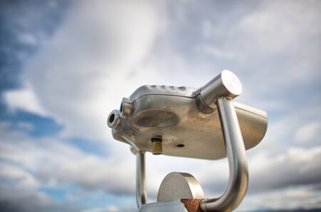 Metal binocular looking to the city, cloudy sky on background.の写真素材