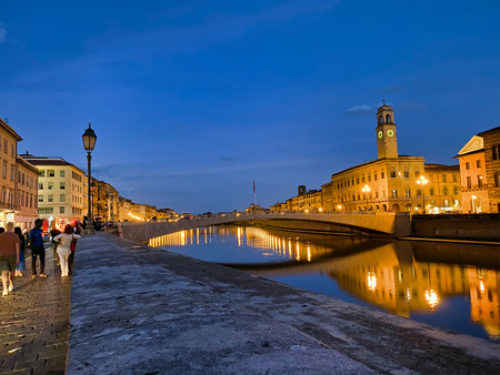 PISA, ITALY - SEPTEMBER 27, 2019: Lungarni with tourists at sunset.のeditorial素材