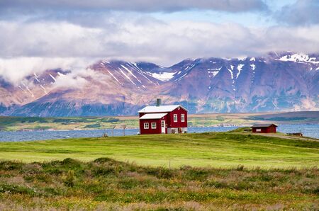 Beautiful red house with mountain landscape in summer season, Iceland.の写真素材
