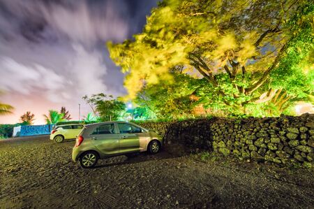 Parked cars along a wall surrounding a beautiful park.の写真素材