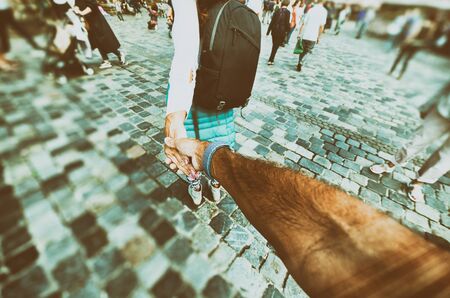 Girl holding man's hand during city visit. Follow me concept, tourism abstract.