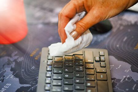 Woman cleaning computer keyboard with soft cloth. Coronavirus prevention and home disinfection.の写真素材