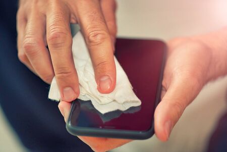 Man cleaning smartphone at home. Coronavirus prevention against virus outbreak.の写真素材