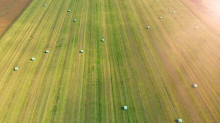 Amazing aerial view of beautiful hay bales on a green meadow.