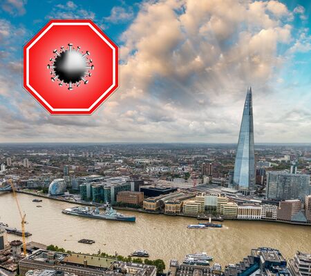 London, UK. Concept image with large red coronavirus warning sign in front of city skyline, travel restriction concept, covid-19 virus outbreak.の写真素材