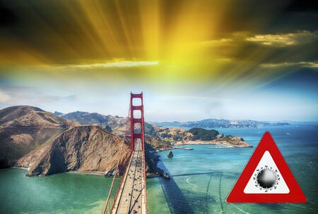 San Francisco, California. Concept image with large red coronavirus warning sign in front of Golden Gate, travel restriction concept, covid-19 virus outbreak.の写真素材