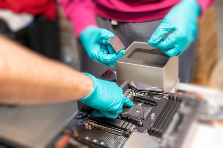 Personal computer technicians mounting processor on the motherboard socket.