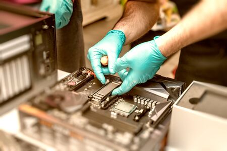 Personal computer technicians mounting ssd drive on the motherboard socket, pc assembling.の写真素材