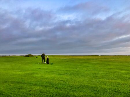 Beautiful gold course with man playing at sunset.の写真素材