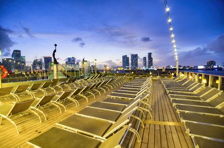 Cruise ship deck chairs at night with city view on the background. Holiday and vacation concept.の写真素材