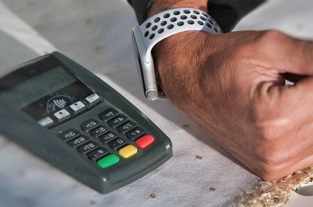Mirror reflection of  contactless payment. Man approaching smartwatch to portable machine.の写真素材