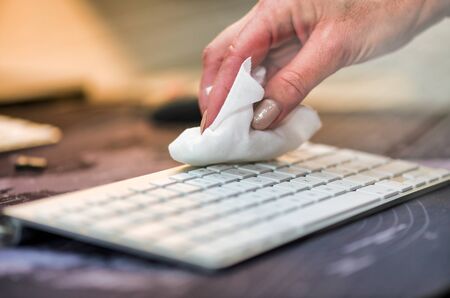 Woman hand cleaning computer keyboard, disinfecting room.の写真素材
