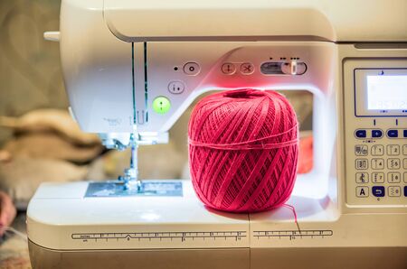 Red color ball of threads wool under sewing machine.の写真素材