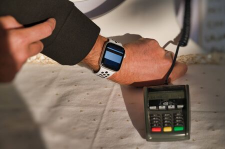 Contactless payment. Man approaching smartwatch to portable machine in a shop.の写真素材