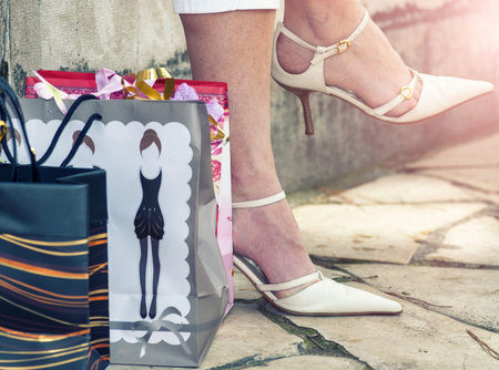 Elegant woman seated on the bench with colorful gift boxes. Shopping sale concept.