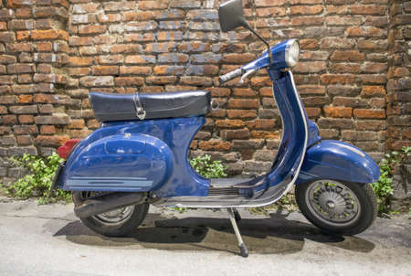 Vintage blue italian motorbike with brick ancient wall on background.の写真素材