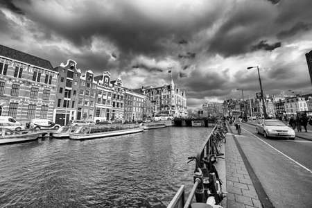 AMSTERDAM, THE NETHERLANDS - APRIL 25, 2015: Traditional houses and buildings on the canal with boats on the water.の写真素材