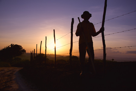 Man standing in the field dressed in hat and cowboy clothes looking at the sunsetの写真素材