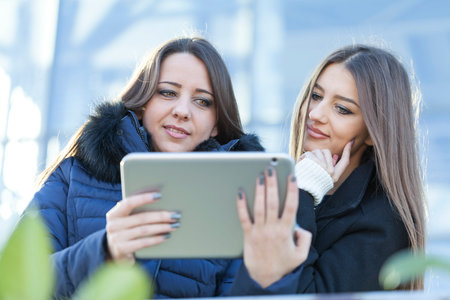 Two young business women with a tablet in hand