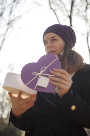 Beautiful young woman with a gift in hand, Selective focus and small depth of field, Lens flareの写真素材