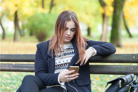 Young girl in a park on a bench listening to music, Selective focus and small depth of field, lens...