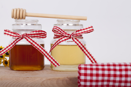 Honey in  jar with honey dipper on a light background, selective focus and small depth of fieldの写真素材