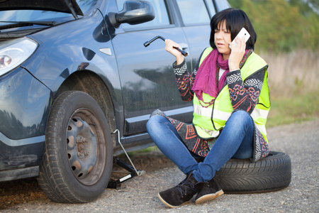 Woman changing a wheel on a car on the empty road, Selective focus and small depth of field
