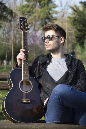 Handsome young man enjoying the park with a guitar.Selective focus and small depth of field.の写真素材