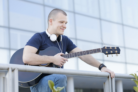 Handsome young man enjoying the outdoors with a guitar.Selective focus and small depth of field.の写真素材