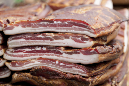 Home made smoked bacon in a street market, bacon cut in bigger pieces. Selective focus and small depth of fieldの写真素材