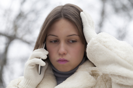 Portrait of a young woman in the park, which phone calls and expressions of of her face shows that is worriedの写真素材