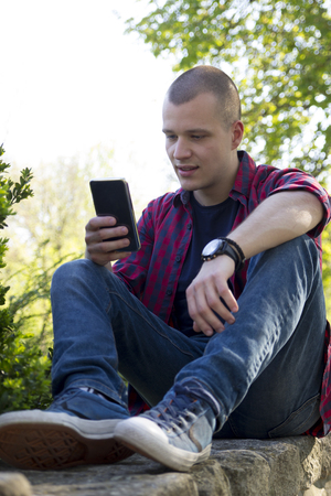Handsome young man holding phone and chat via mobile phone. Selective focus and small depth of field.の写真素材