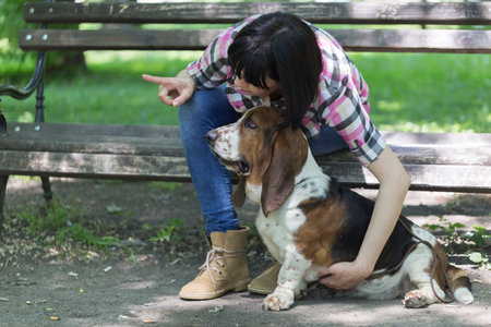 She loves her dog. Woman sits on a bench in the park with his beautiful dog and shows him which way to look.の写真素材