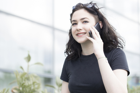 Young beautiful woman talking on a mobile phone on the street in the cityの写真素材