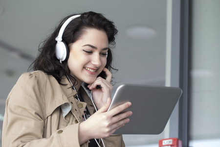 Young beautiful girl, student, listening to music and holds in her hand tablet.の写真素材