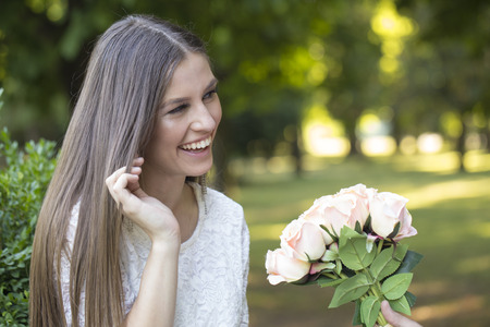 Portrait of a beautiful young woman who receives a gift, a bouquet of wonderful rosesの写真素材