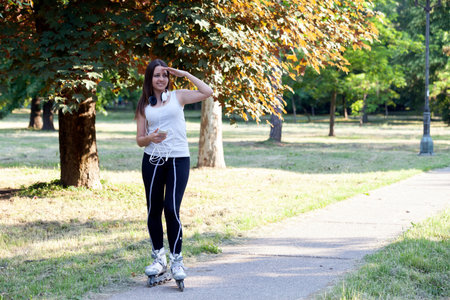 Young beautiful women ride on roller skates in the park and view the environment.