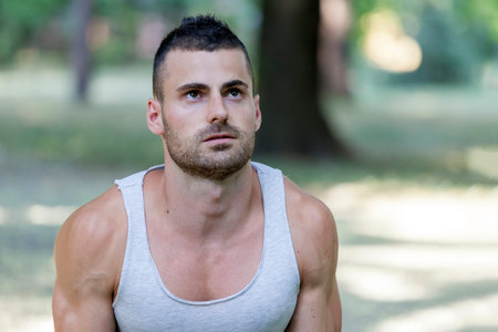 Young sportsman doing  exercise, preparing for morning training in the park. Fitness, sport, lifestyle conceptの写真素材