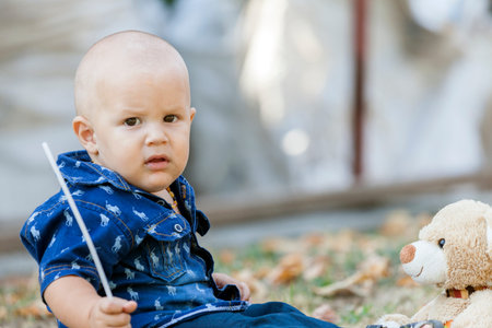 Portrait of a sweet little boy while sitting and playing with his favorite toy. He likes to spend time outdoors and play. He just learned to walk. Childhood, growing up, summer sunny day. Copy spaceの写真素材