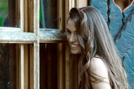 Beautiful young woman standing by the window. She is happy and smilingの写真素材
