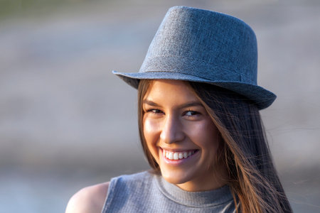 Close up portrait of happy smiling young girl with a hat outdoors.Copy space